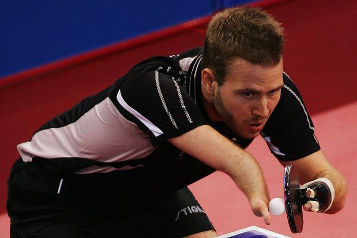 A male Para table tennis player prepares to serve the ball.