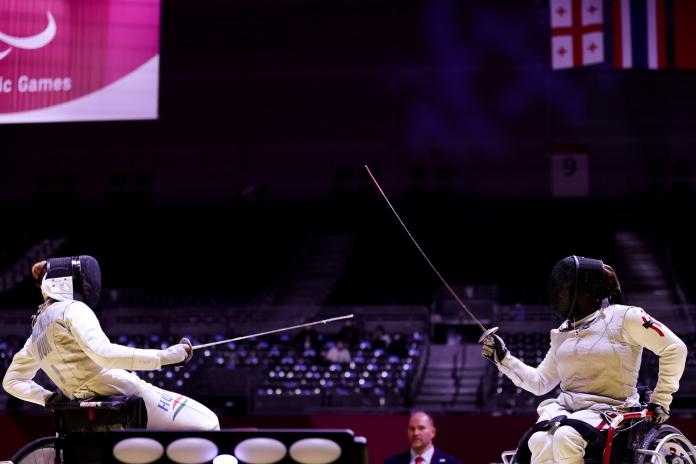Two female wheelchair fencers point their foils at each other during a bronze medal match.