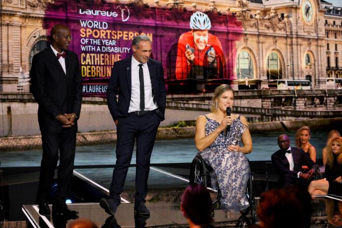 A female wheelchair athlete makes a speech on a stage.