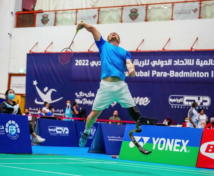 A male athlete with a prosthetic blade jumps during a badminton match