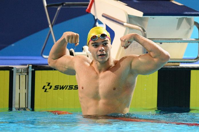 A male swimmer strikes a pose in the pool after his race.