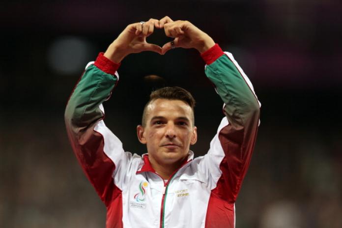A male athlete wearing Portugal's uniform makes a heart shape above his head with his hands