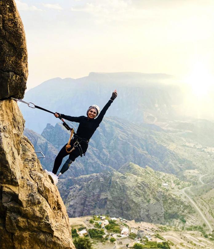 A woman with a prosthetic leg climbs a mountain