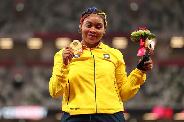 A female athlete holds a gold medal with her right hand and poses for a photo at the Tokyo 2020 Paralympic Games.
