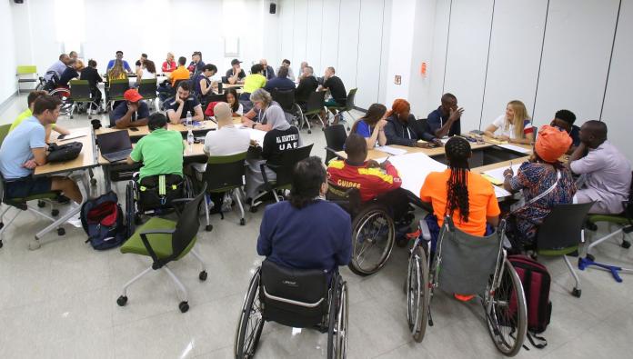 The photo shows a room with three tables. About 10 people are sitting at each table and taking part in discussions.