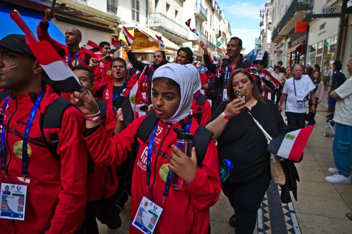 A group of people wearing red uniforms takes part in a parade