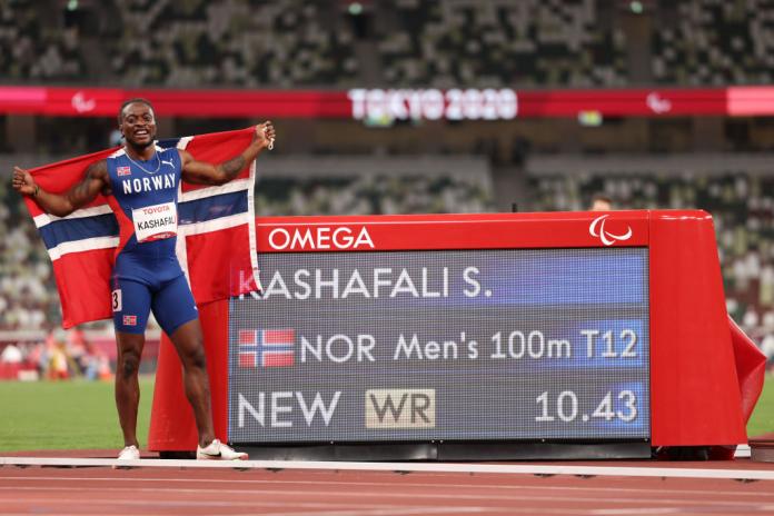 Salum Ageze Kashafal holds up the Norwegian flag next to his world record time