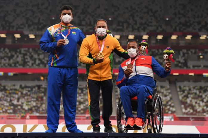 Yogesh Kathuniya, Claudiney Batista dos Santos, Leonardo Diaz Aldana wearing masks and medals on the podium