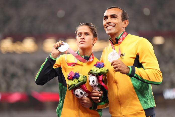 Thalita Vitoria Simplicio da Silva and her guide hold up their silver medals and smile