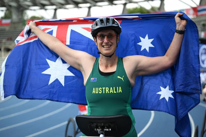 An Australian athlete celebrates holding up their flag 