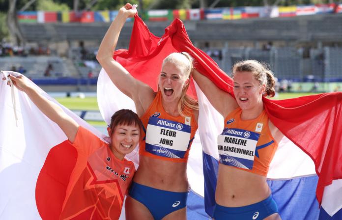 Fleur Jong celebrating in the centre of other athletes, holding up the Dutch flag