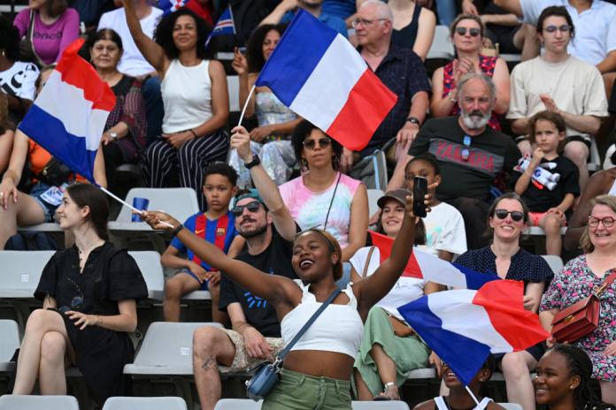 a female spectator cheering and waving French flags 