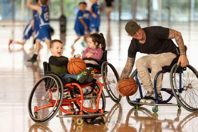 a child in a wheelchair playing with a basketball and smiling 