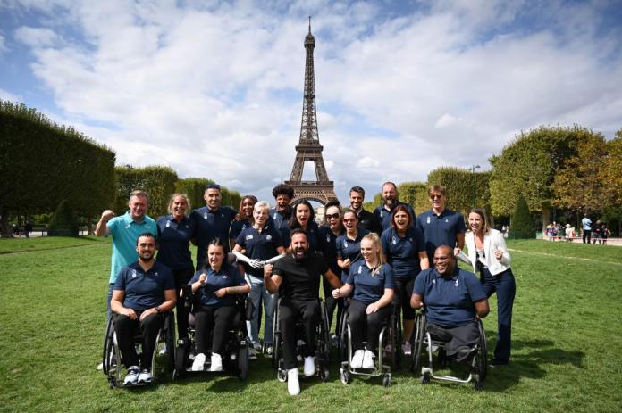 A group of about 20 people posing for a photo in front of the Eiffel Tower.