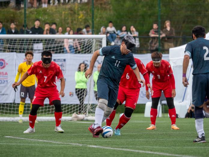 A male athlete wearing a blind fold plays blind football.