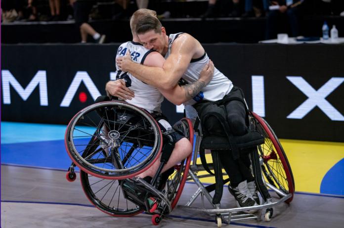 Twee mannelijke rolstoelbasketbalspelers knuffelen