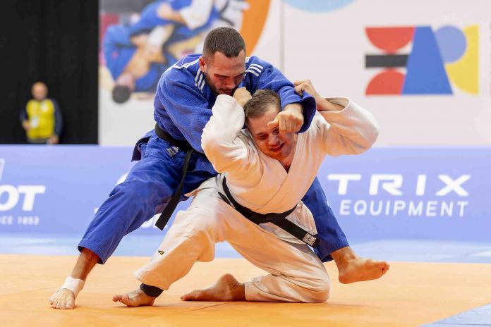 Two Para judokas grappling on the mat