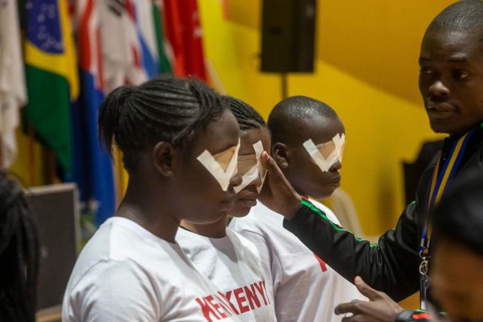 Kenyan goalball players having their eyes taped by their coach 