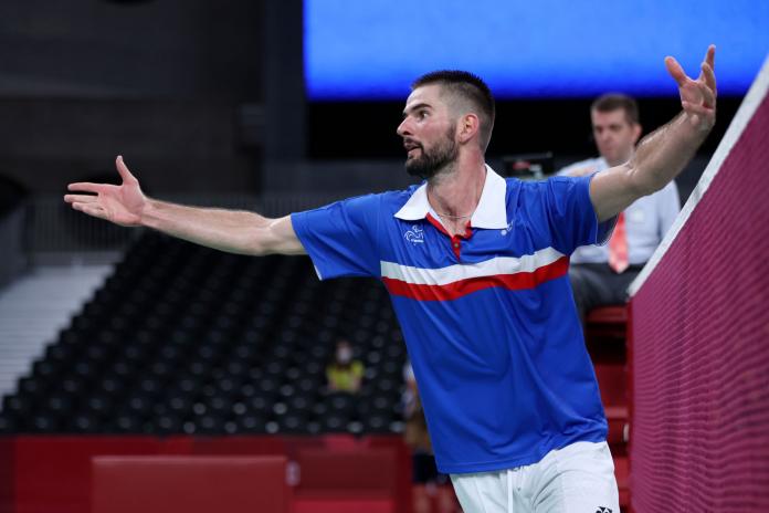 A male athlete opens his arms to celebrate after a win.