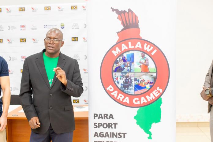 a man speaking alongside the Malawi Para Games logo