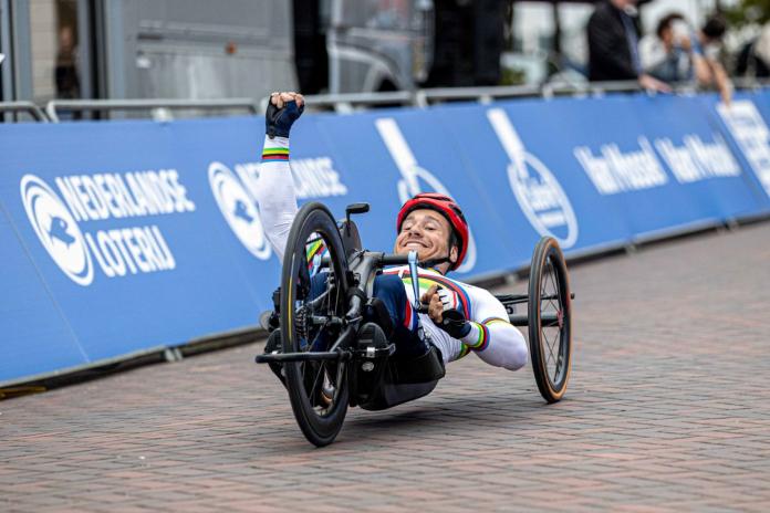 A male athlete on a handcycle pumps his right fist