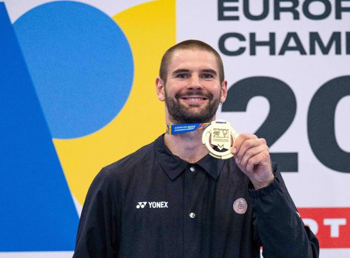 Para badminton player Lucas Mazur holding up his gold medal and smiling