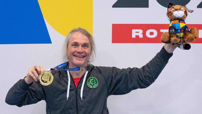 Para badminton player Thomas Wandschneider holds up his gold medal and mascot