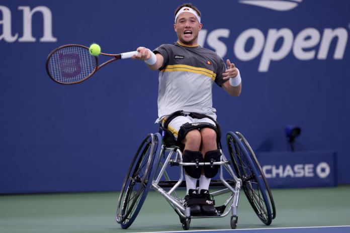 A male wheelchair tennis player hits the ball