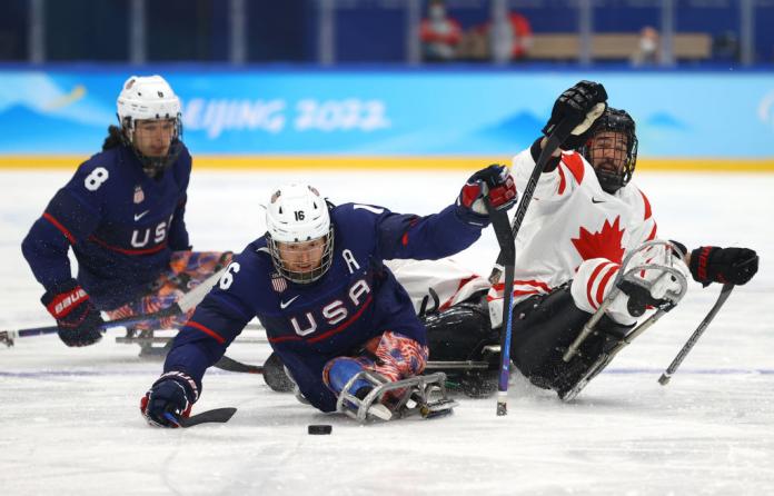 Three male Para ice hockey players playing