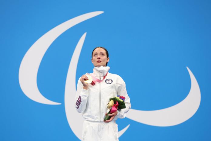 A female athlete looking up holding the gold medal