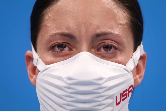 A close-up image of a female Para athlete's face. She is wearing a face mask and tears filling her eyes.