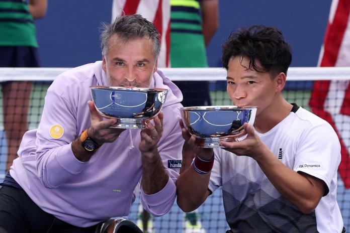 Two male wheelchair tennis players pose for a photo with their US Open trophies.