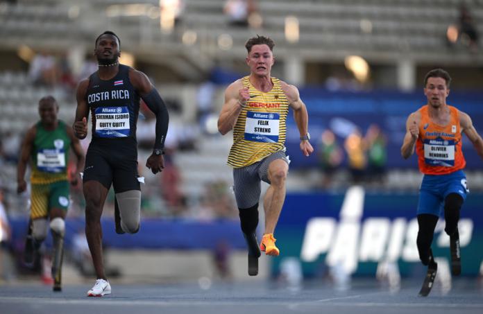 Three male Para athletes with running blades compete in the 100m race.