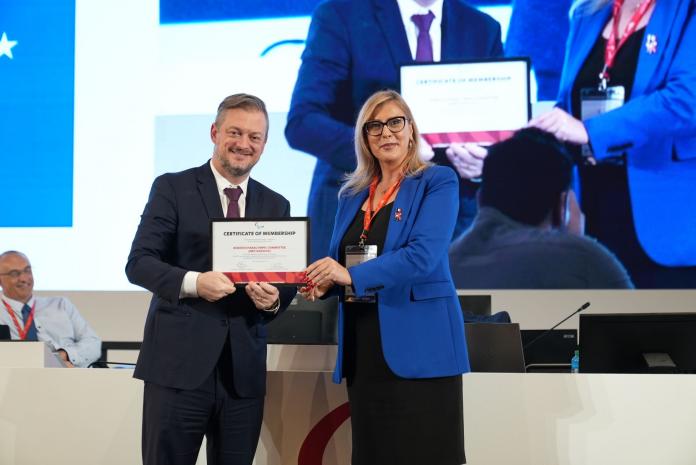 Andrew Parsons, IPC President, hands a certificate of membership to a female representative of NPC Kosovo