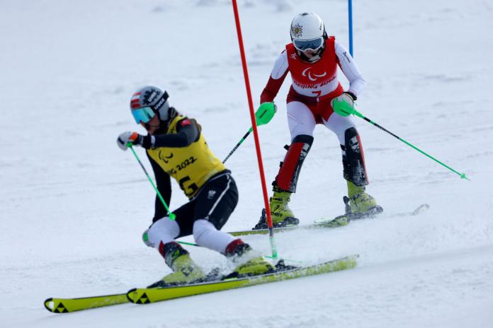 Two female athletes competing in Para alpine skiing.