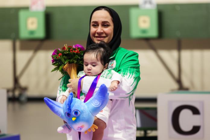 A female athlete holds her baby on the podium