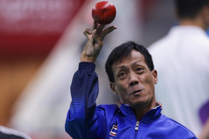 A male boccia athlete throws a red ball