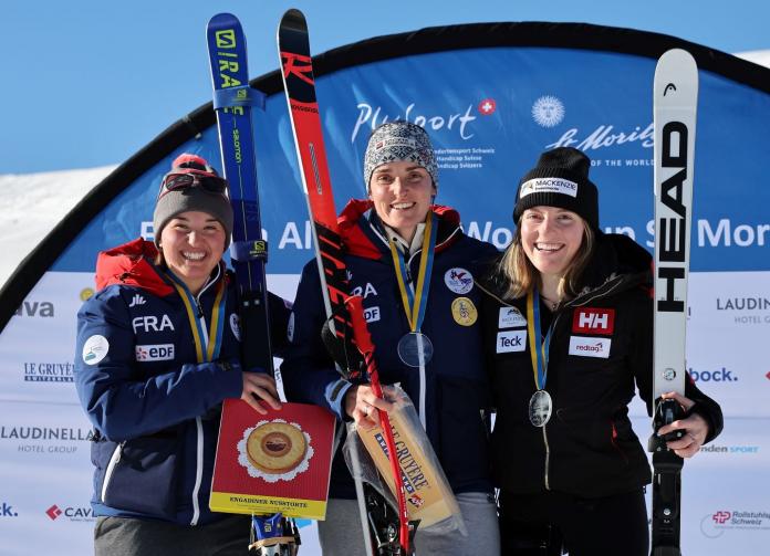 Three skiers pose on a podium.