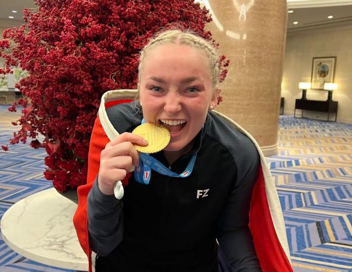 A female athlete bites a gold medal