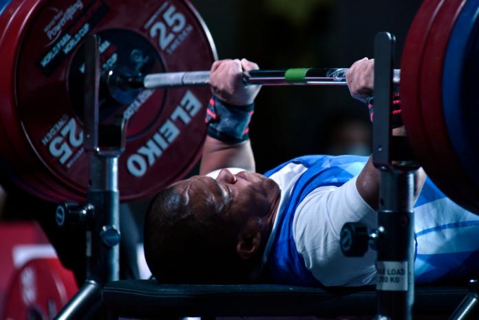 A male Para powerlifter lifts weight during a competition