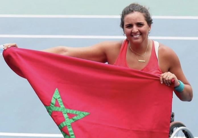 A female wheelchair tennis player holds the flag of Morocco
