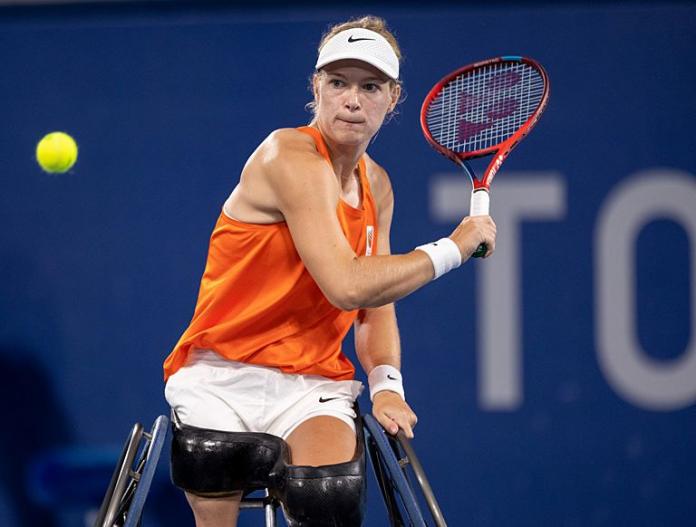 A female wheelchair tennis player prepares to hit a ball during a game.