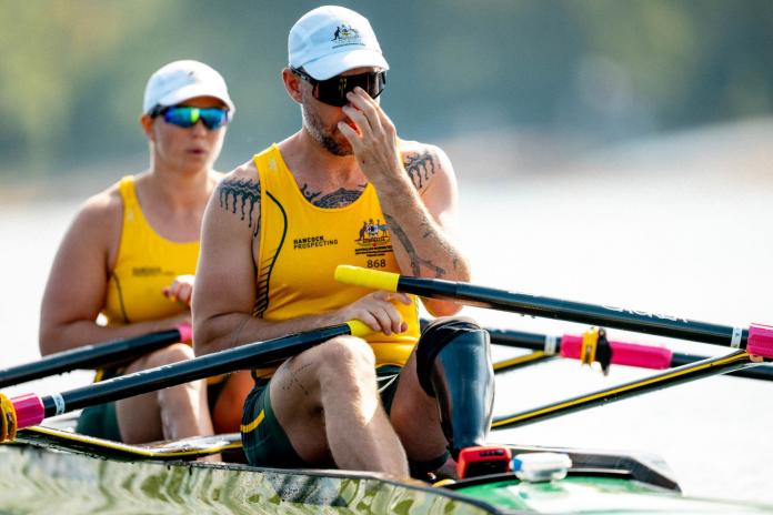Two Para rowers - a male athlete and a female athlete - are sitting on a boat.