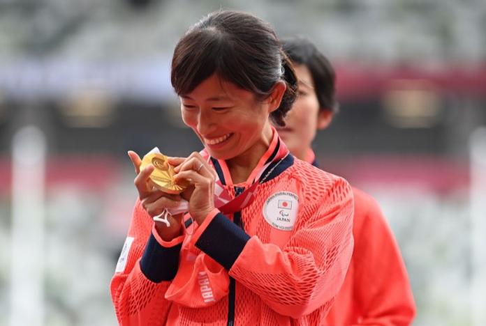 A female athlete reads the braille letters on her gold medal at the Tokyo 2020 Paralympics.