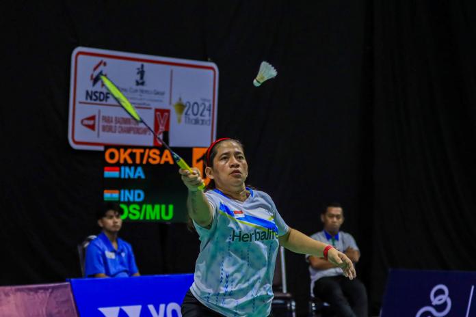 A female Para badminton player reaches for the shuttle during a Para badminton match