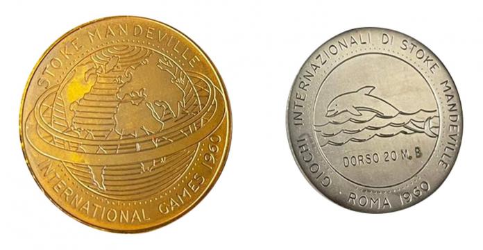 The photo shows a gold medal from Rome 1960 in the left and a silver medal in the right. The gold medal has an image of the globe with the words "Stoke Mandeville International Games 1960. The silver medal has an image of a dolphin engraved.
