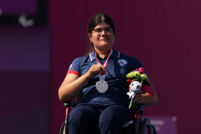 Para archer Mariana Zuniga holding up her silver medal on the podium 