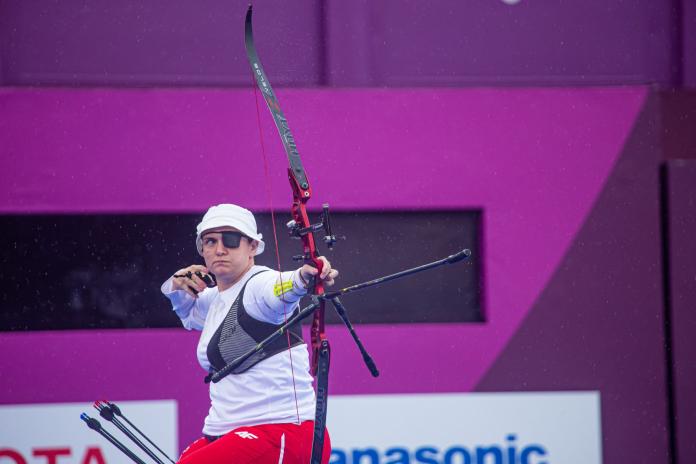 The photo shows a female archer after shooting an arrow.