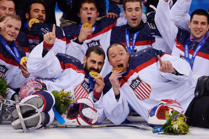 About 10 male ice sledge hockey athletes celebrate after receiving their gold medals.