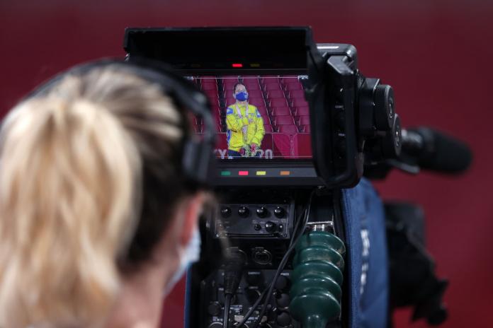 A TV Video camera shows a female athlete with her gold medal